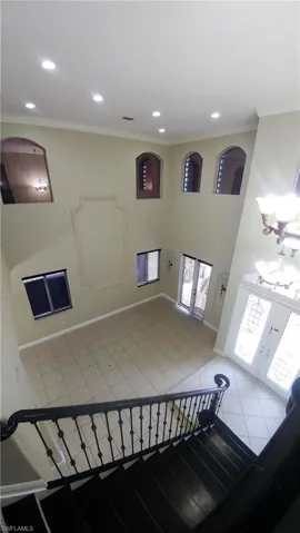 Stairway featuring crown molding, tile patterned flooring, french doors, a high ceiling, and recessed lighting