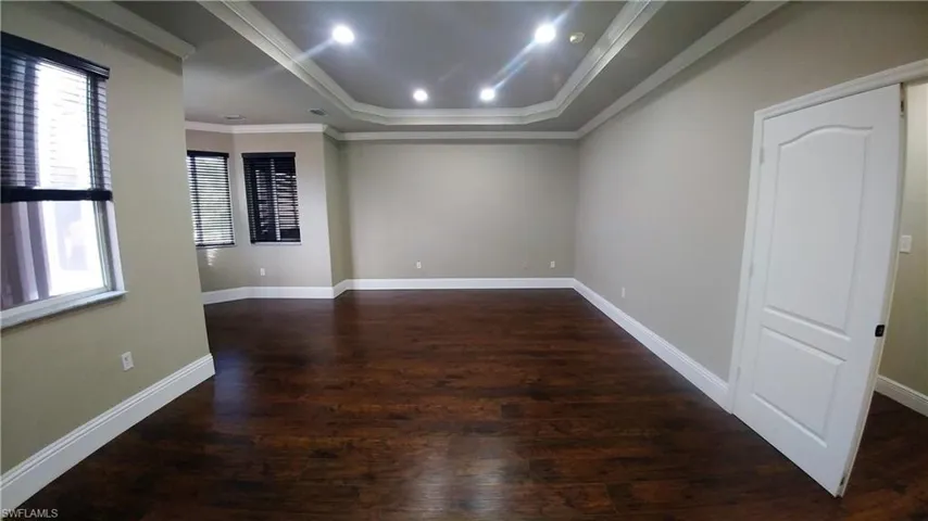 Huge Primary Bedroom features a tray ceiling, wood-style flooring & ornamental molding
