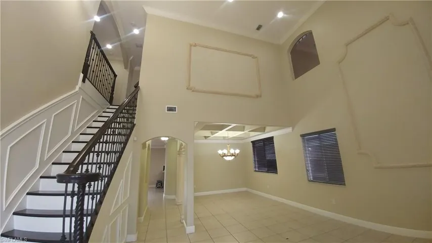 Huge Living & Dining w/Volume Celing, arched walkway, crown molding, stairway, recessed lighting, and the dining room chendelier suspended from the coffered ceiling.
