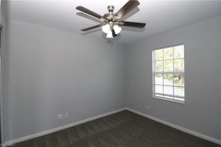 Carpeted empty room featuring ceiling fan