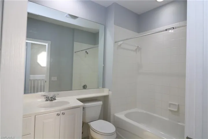 Full bathroom featuring tiled shower / bath, oversized vanity, and toilet