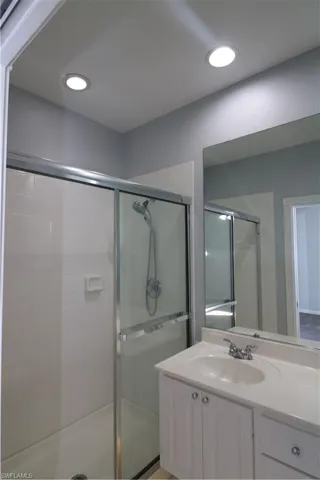 Bathroom featuring a shower with door and large vanity