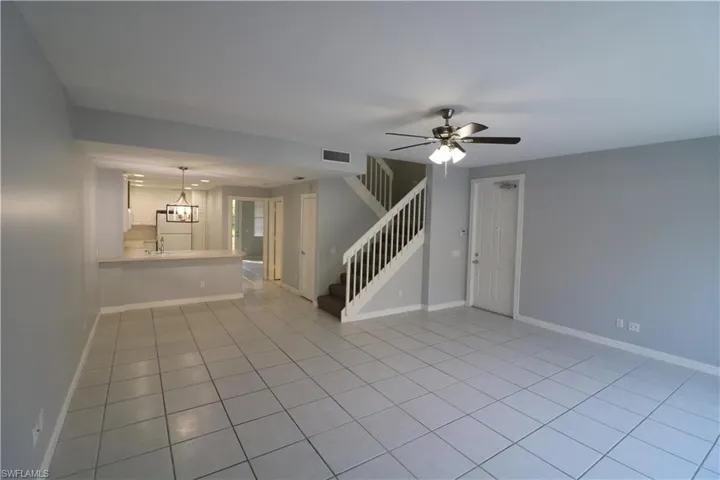 Unfurnished living room with ceiling fan, light tile flooring, and sink