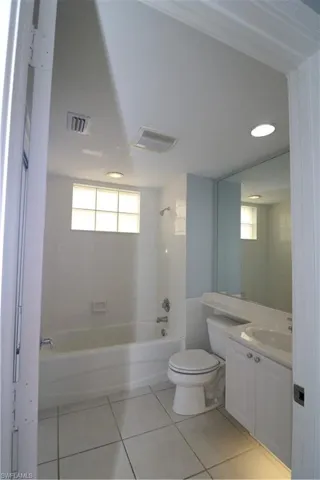 Full bathroom featuring tile floors, vanity, toilet, and tiled shower / bath combo