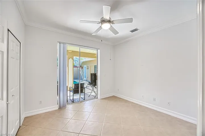 Tiled spare room featuring ceiling fan and ornamental molding
