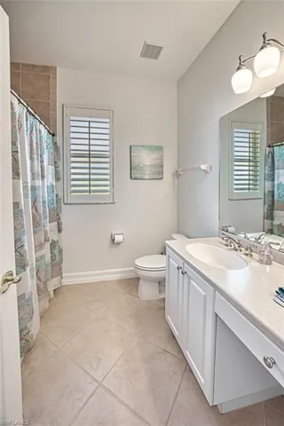 Bathroom with toilet, vanity, and tile patterned floors