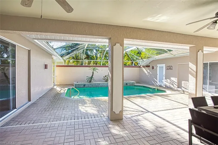 View of swimming pool with ceiling fan, a patio area, and glass enclosure