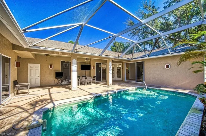 View of pool with a patio, glass enclosure, and ceiling fan