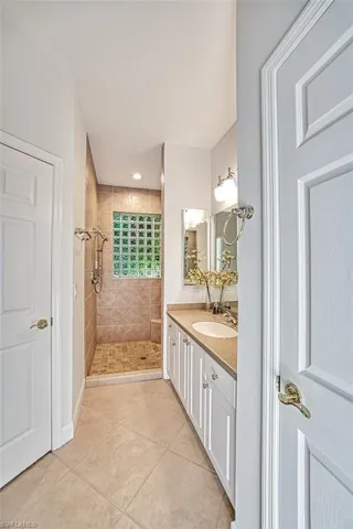 Bathroom featuring tiled shower, vanity, and tile patterned flooring
