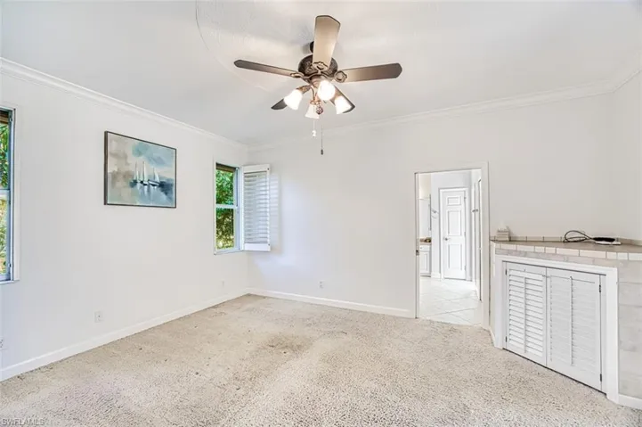 Unfurnished room featuring ceiling fan, light colored carpet, and crown molding