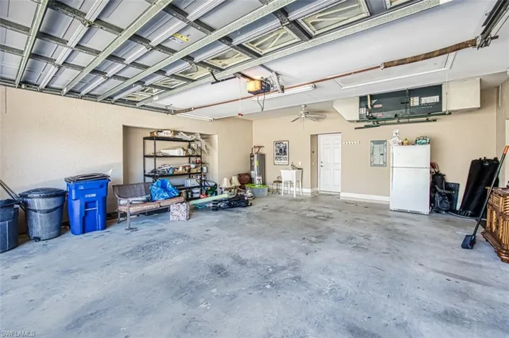 Garage featuring ceiling fan, sink, gas water heater, white refrigerator, and a garage door opener