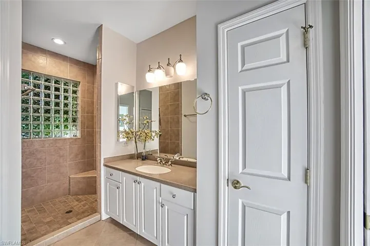 Bathroom featuring tile patterned flooring, vanity, and tiled shower