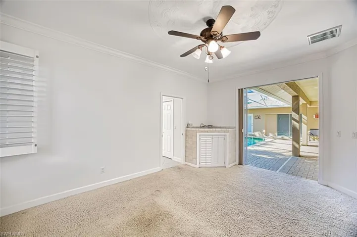 Unfurnished bedroom featuring access to outside, ceiling fan, carpet, and ornamental molding