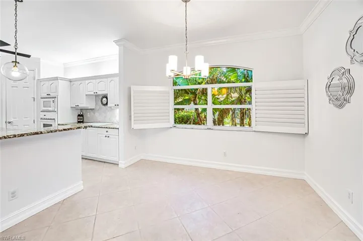 Kitchen featuring pendant lighting, white appliances, white cabinetry, and light stone counters