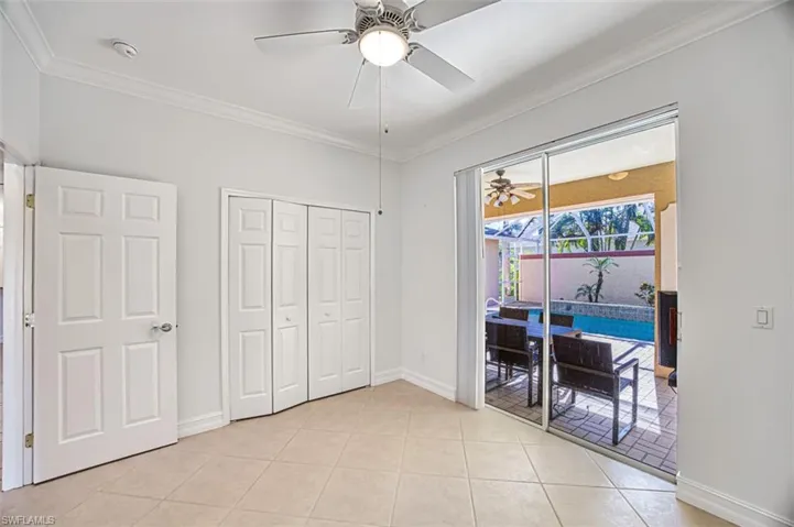 Tiled bedroom with ceiling fan, crown molding, access to outside, and a closet
