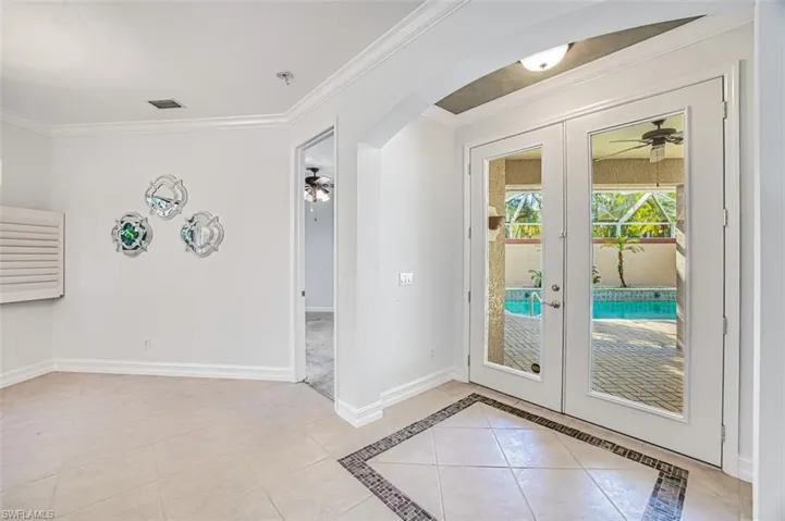 Entryway with french doors, light tile patterned floors, ceiling fan, and crown molding