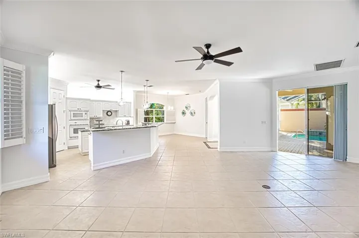 Unfurnished living room with ceiling fan, a healthy amount of sunlight, light tile patterned floors, and crown molding