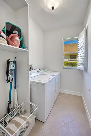 Laundry room featuring light tile patterned flooring and washing machine and clothes dryer