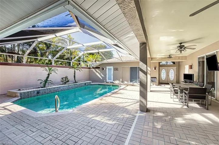 View of swimming pool with ceiling fan, a lanai, and a patio