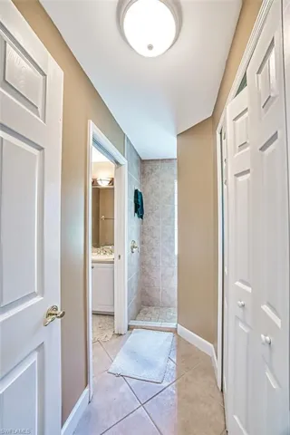 Bathroom with tiled shower and tile patterned floors