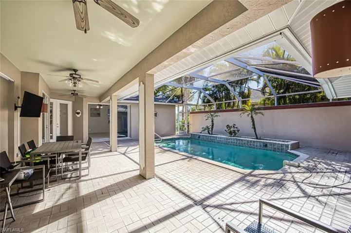 View of swimming pool featuring glass enclosure, ceiling fan, and a patio area