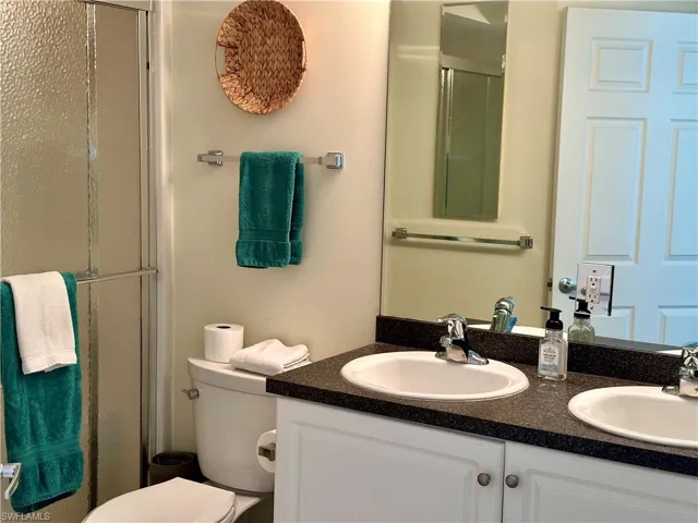 The en suite bath has double sinks, toilet, and a shower.