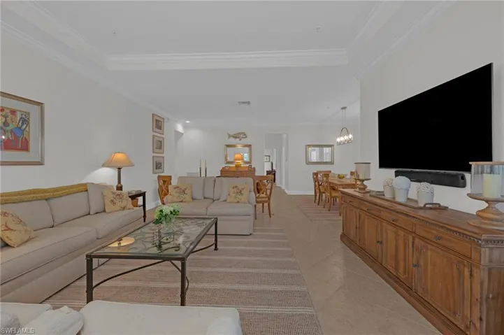 Living room featuring light tile patterned floors, a chandelier, and ornamental molding