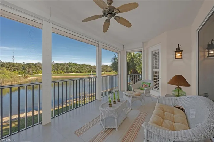 Sunroom / solarium featuring ceiling fan, a water view, view of wooded area, and a patio area