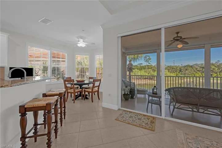 Dining area with a ceiling fan, light tile patterned floors, and crown molding