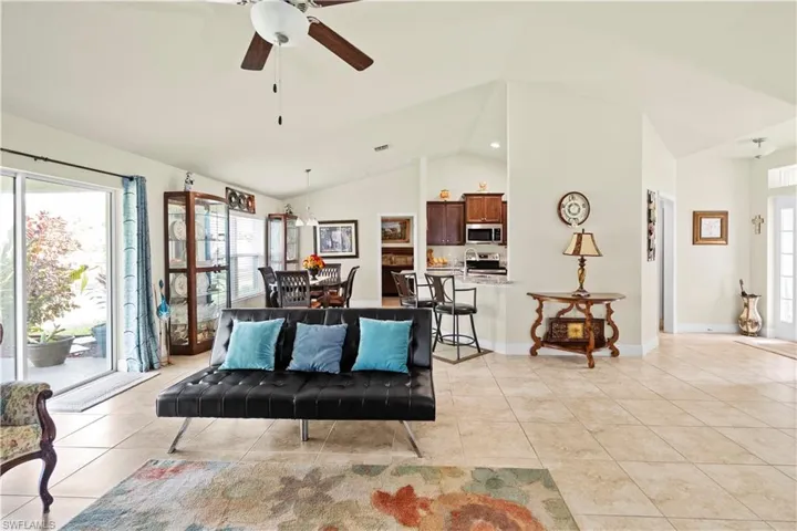 Living area with healthy amount of natural light, light tile patterned floors, a ceiling fan, and high vaulted ceiling