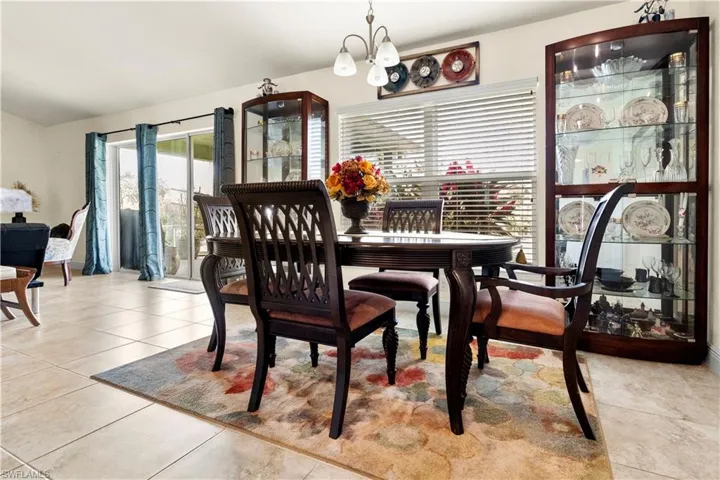 Dining room with healthy amount of natural light, a chandelier, light tile patterned flooring, and vaulted ceiling