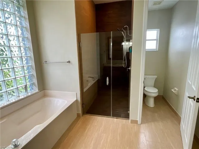 Full bathroom featuring a garden tub, a shower stall, and light wood finished floors