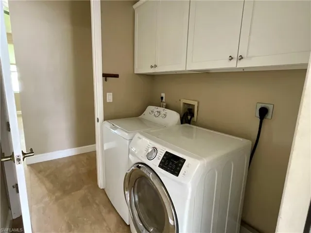 Washroom featuring cabinet space and washing machine and dryer