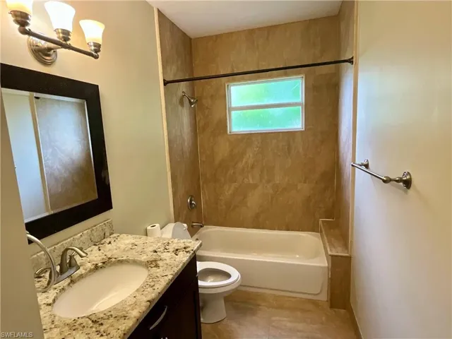 Bathroom with shower / tub combination, vanity, a chandelier, and light tile patterned flooring