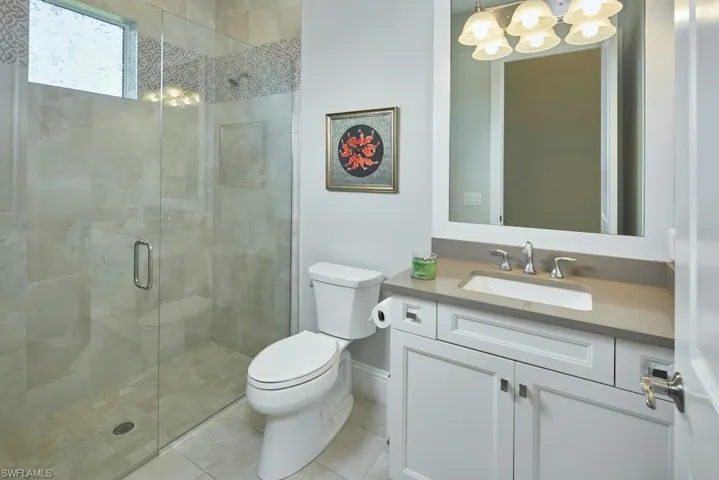 Bathroom featuring vanity, a shower with shower door, toilet, and tile patterned flooring