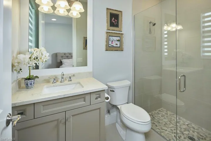 Bathroom with a chandelier, an enclosed shower, vanity, and toilet