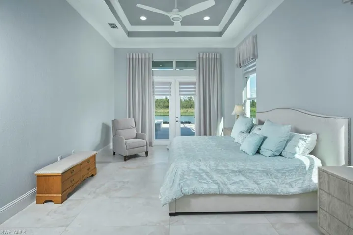 Bedroom featuring ceiling fan, a raised ceiling, ornamental molding, french doors, and access to exterior