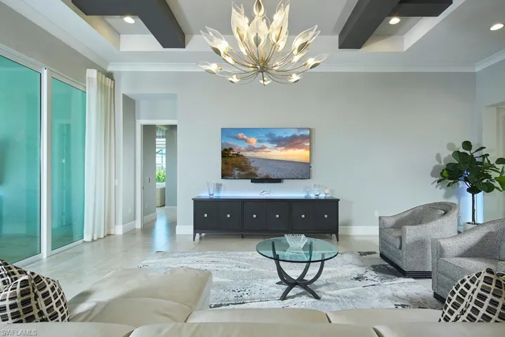 Living room with light tile patterned flooring, a chandelier, and ornamental molding