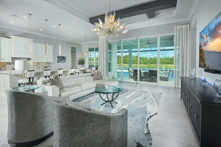 Living room with an inviting chandelier, light tile patterned floors, ornamental molding, and sink