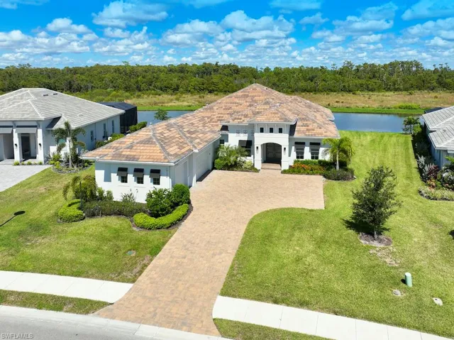 View of front facade with a garage, a water view, and a front lawn