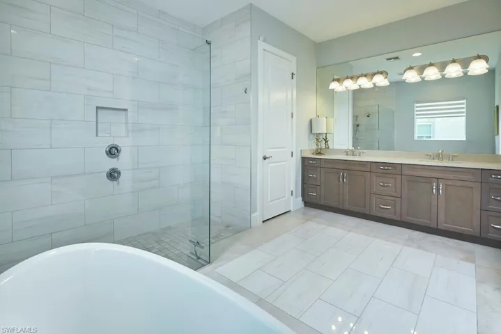 Bathroom featuring tile patterned floors, vanity, and separate shower and tub