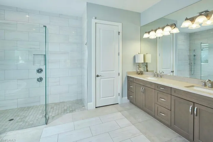 Bathroom featuring vanity, tile patterned flooring, and a tile shower