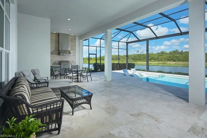 View of patio / terrace featuring grilling area, glass enclosure, and a water view