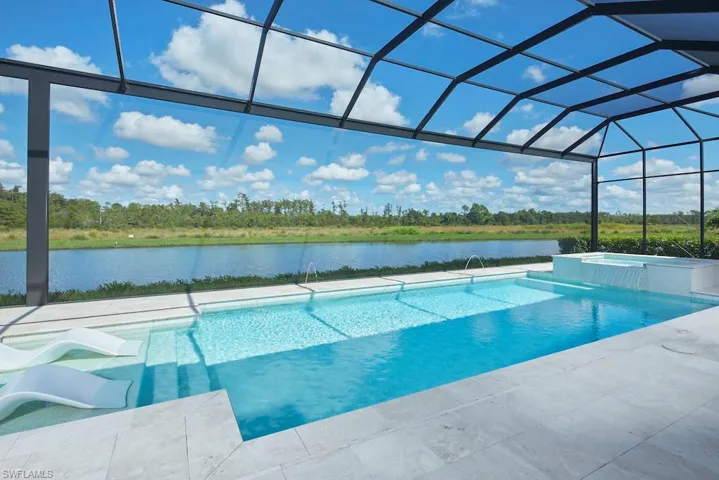 View of pool with a water view, glass enclosure, an in ground hot tub, and a patio area