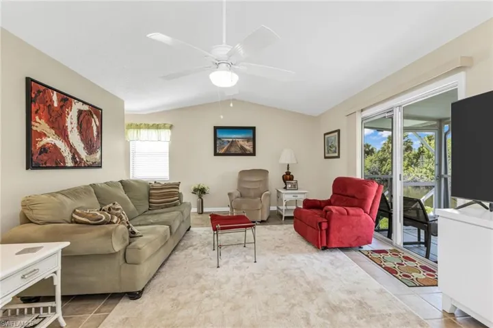 Living area featuring lofted ceiling, a ceiling fan, and light tile patterned floors
