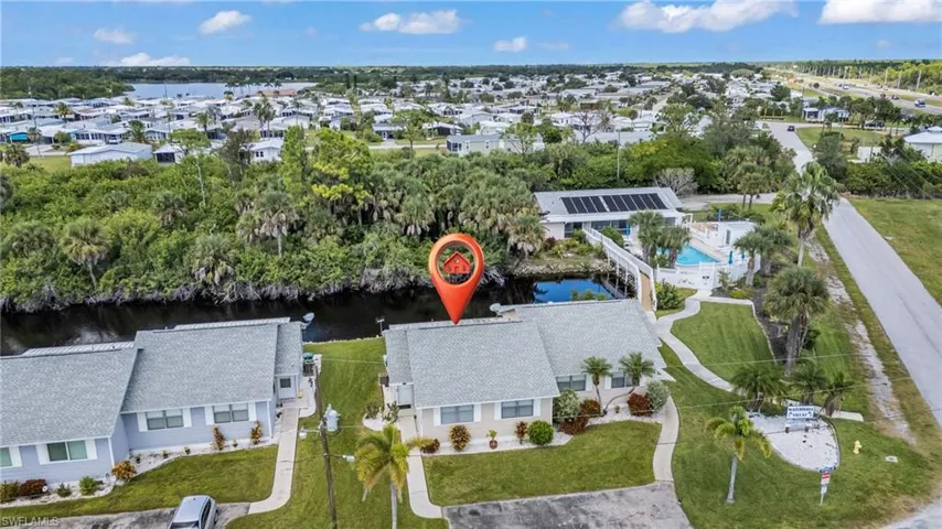 Aerial perspective of suburban area with a nearby body of water and a tree filled landscape