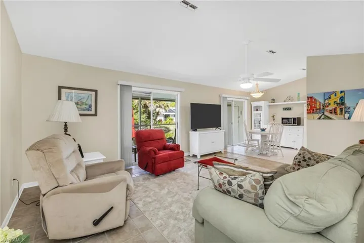Living area with vaulted ceiling, tile patterned flooring, and ceiling fan
