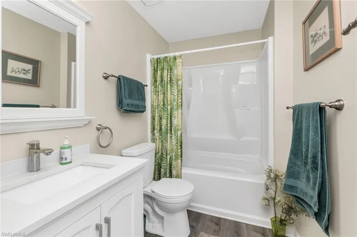 Bathroom with shower / bath combo with shower curtain, vanity, dark wood finished floors, and a textured ceiling