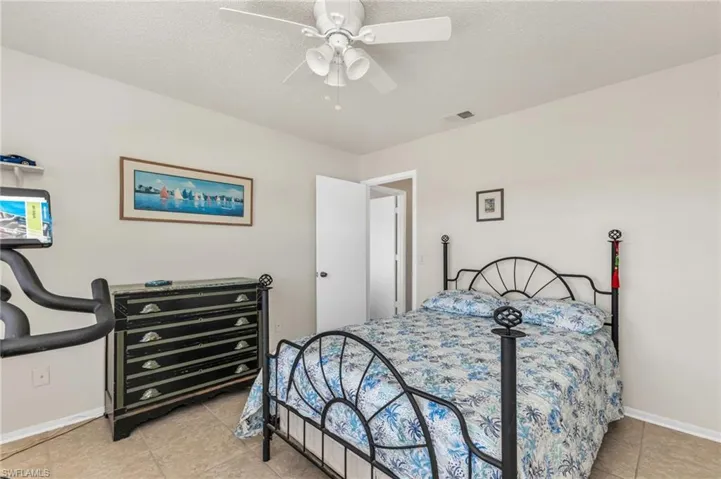 Bedroom featuring ceiling fan, light tile patterned flooring, and a textured ceiling