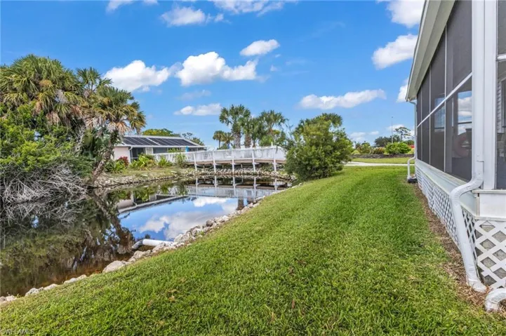 View of grassy yard featuring a sunroom, a water view, and a lanai